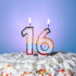 Tasty cake with candles for sixteenth birthday on blue background