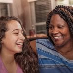 Multi-ethnic family.  Teenage girls and mom at home.  Hugs.