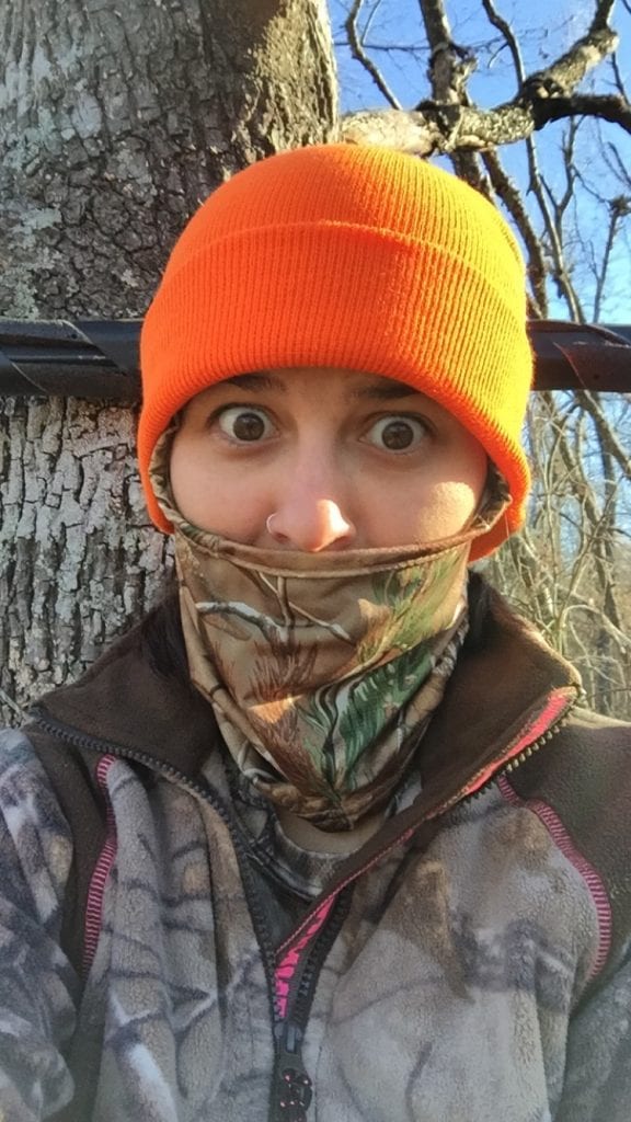 woman in camouflage gear with orange hat 