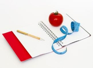 notebook with pen, measuring tape and apple