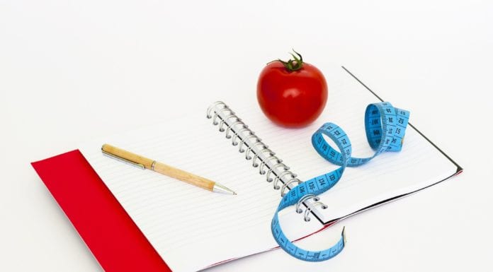 notebook with pen, measuring tape and apple